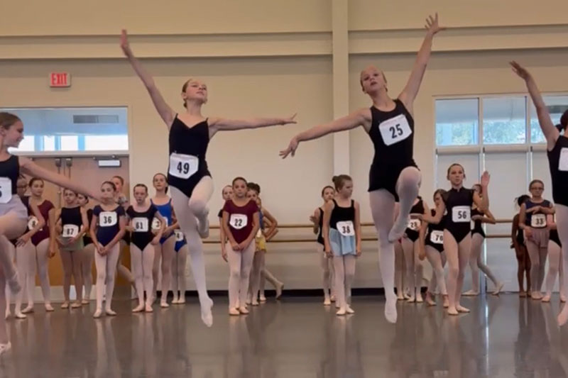 Dancers taking turns to leap for auditions.
