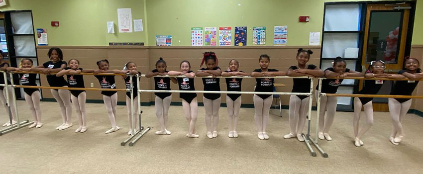 Young dancers standing at the barre.