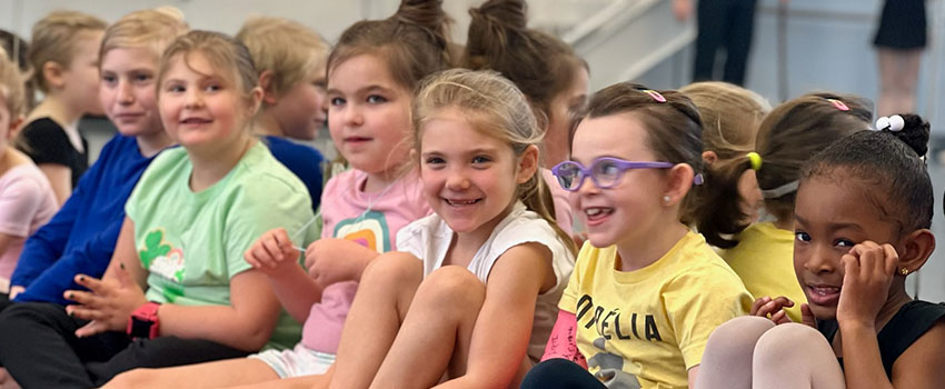 Children watching performers in a ballet studio.