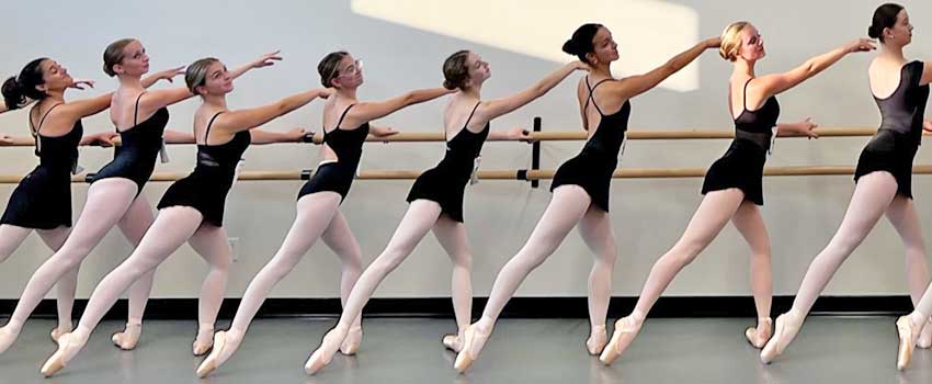 Advanced dancers at the barre in a line all in plie tendu position.