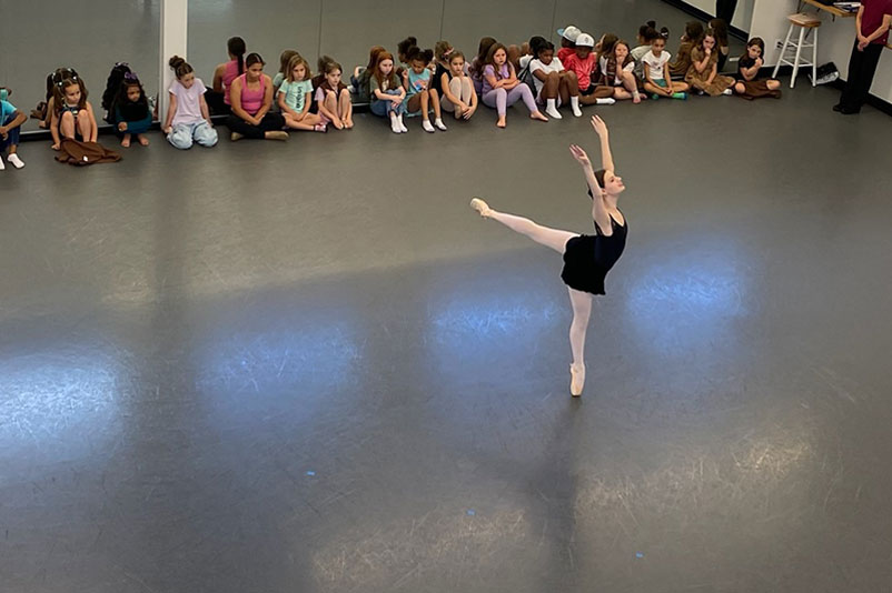 Dancer in arabesque performing for kids in a studio